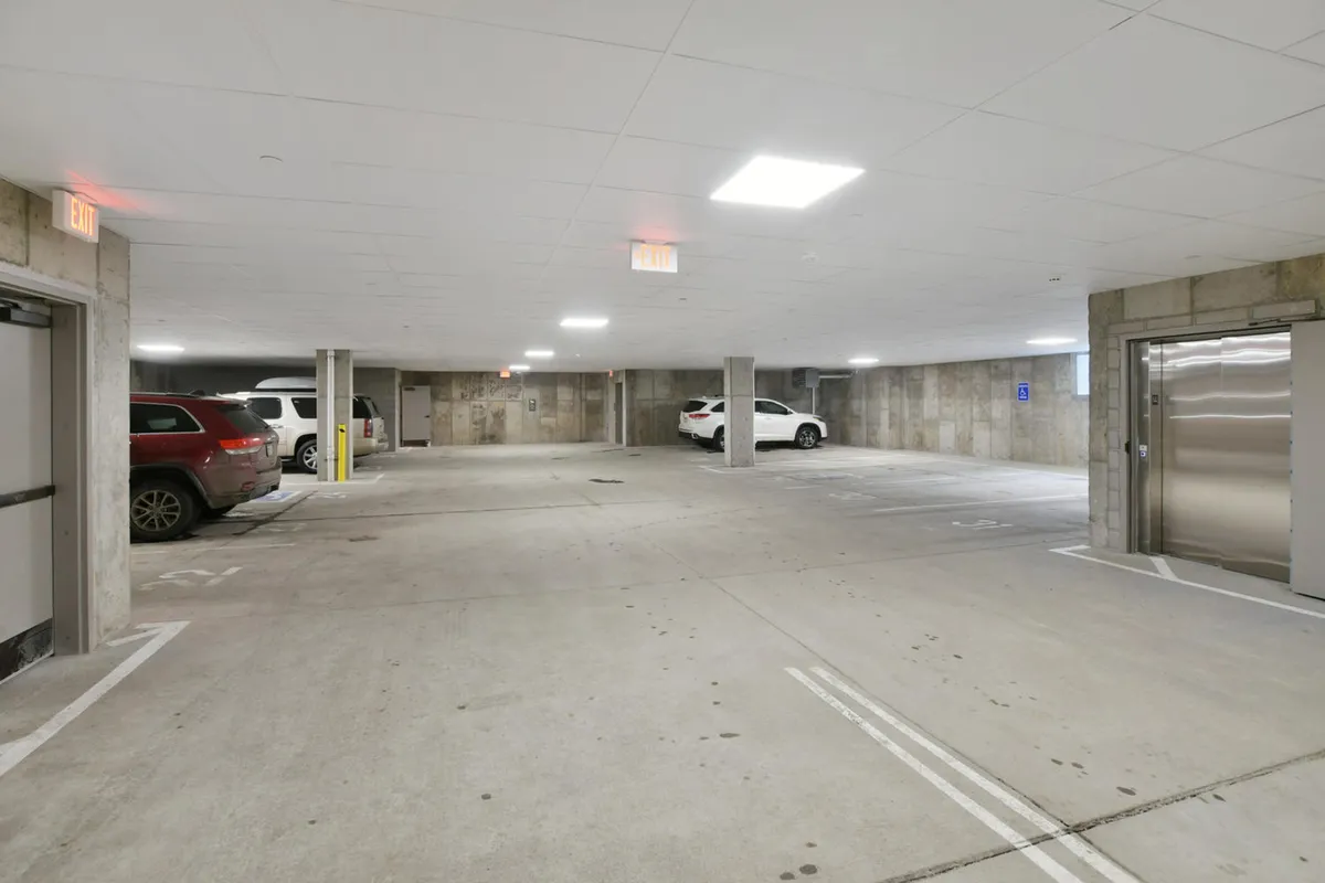 An underground garage with clearly marked parking spaces and vehicles, illuminated by overhead lights. The area appears clean and secure, providing convenient access for guests coming and going from their adventures.